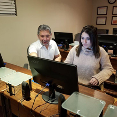 A man and a woman are sitting in front of an acer computer