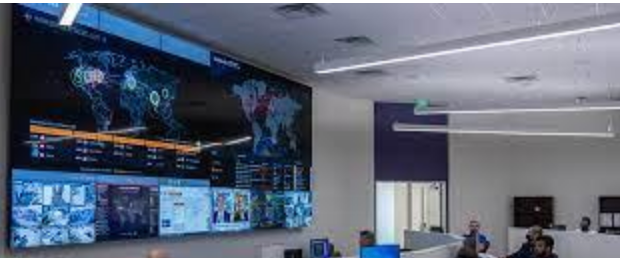 A group of people are sitting in front of a large screen in a room.