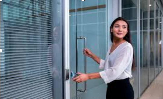 A woman is opening a glass door with a key.