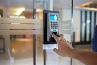 A person is using a fingerprint scanner to open a glass door.