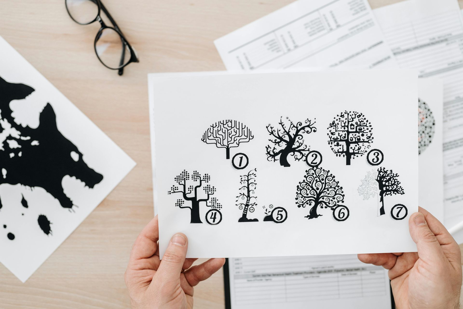 A person is holding a piece of paper with trees on it.