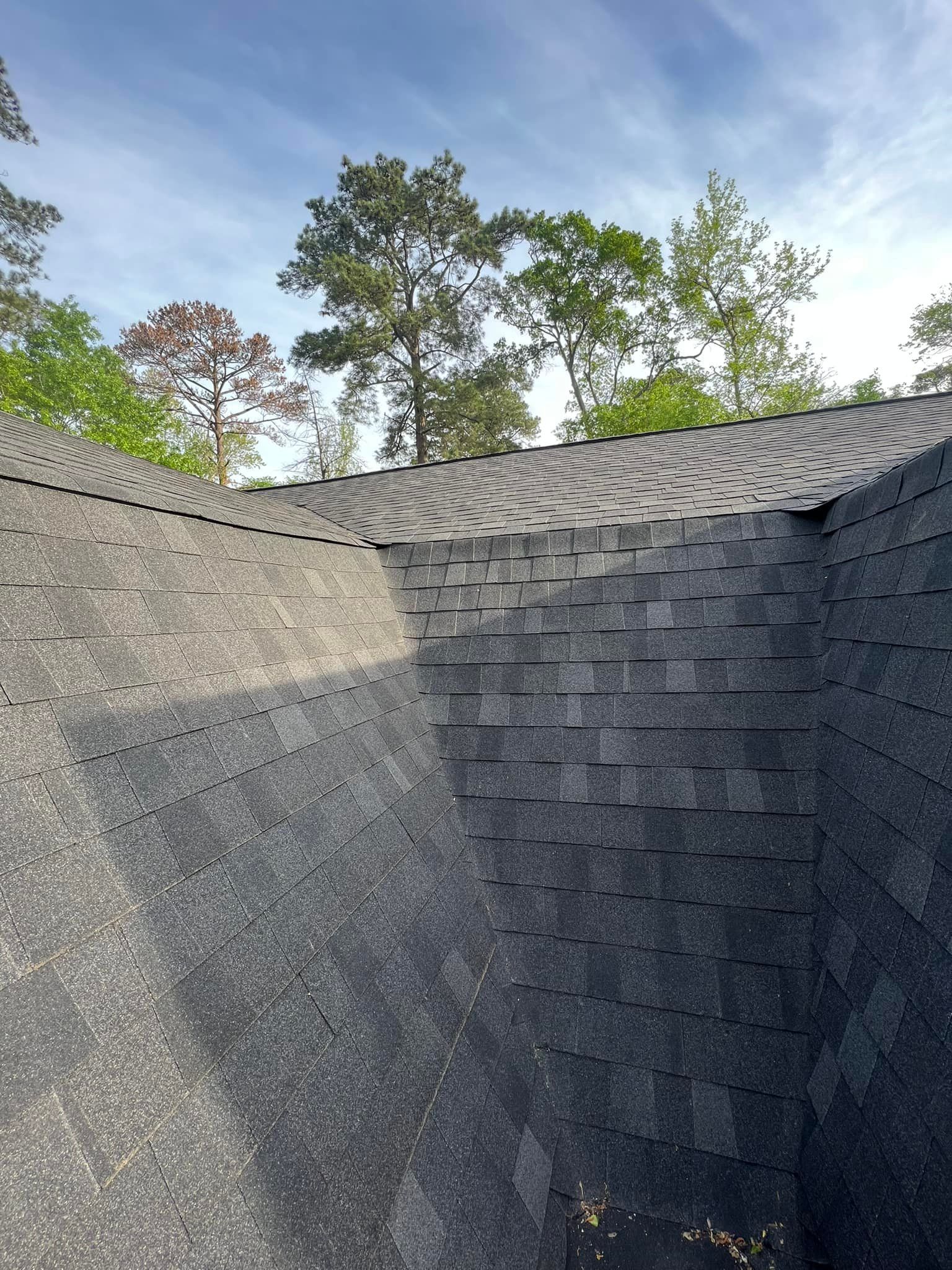 A roof with a lot of shingles on it and trees in the background.