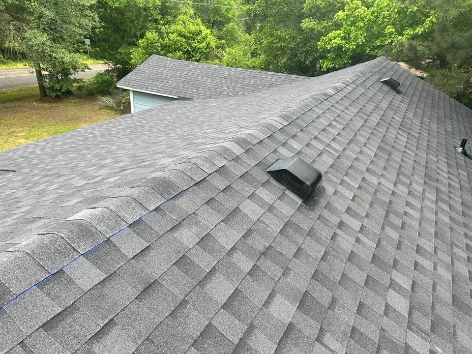 A roof with a lot of shingles on it and trees in the background.