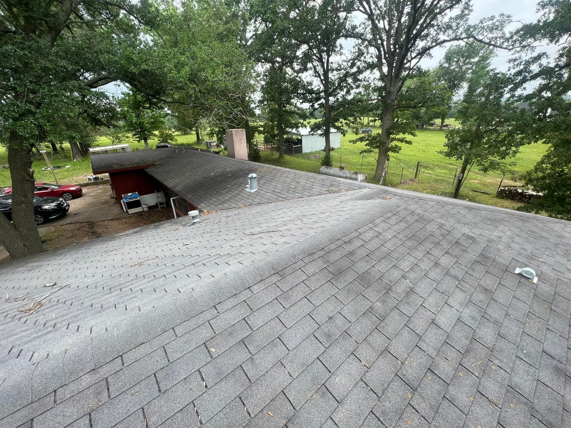 An aerial view of a roof of a house with trees in the background.