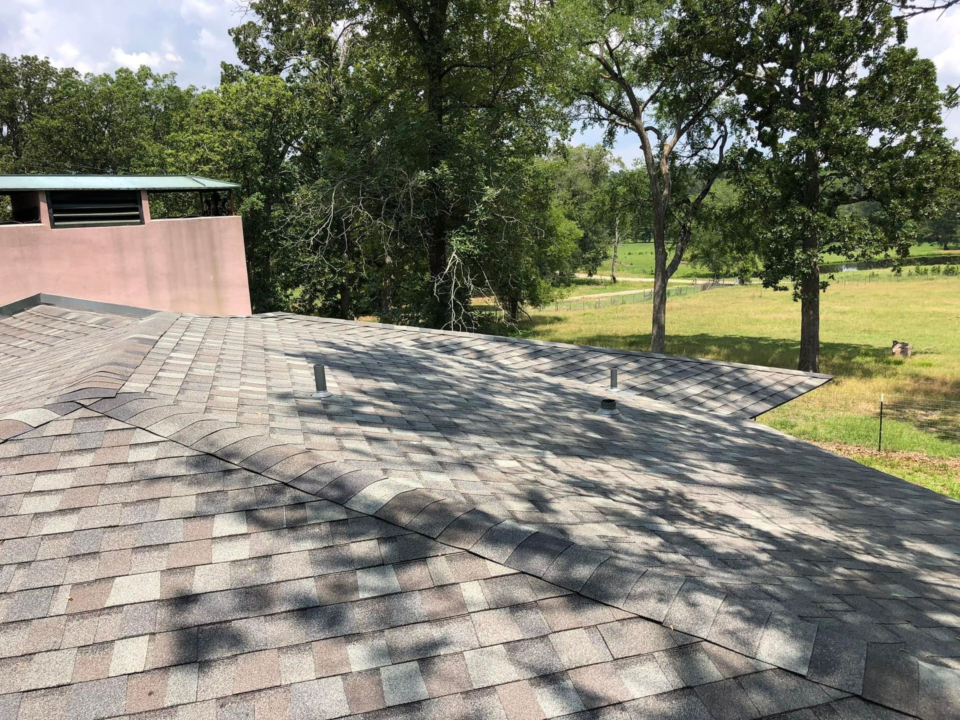 A roof with a chimney on it and trees in the background.