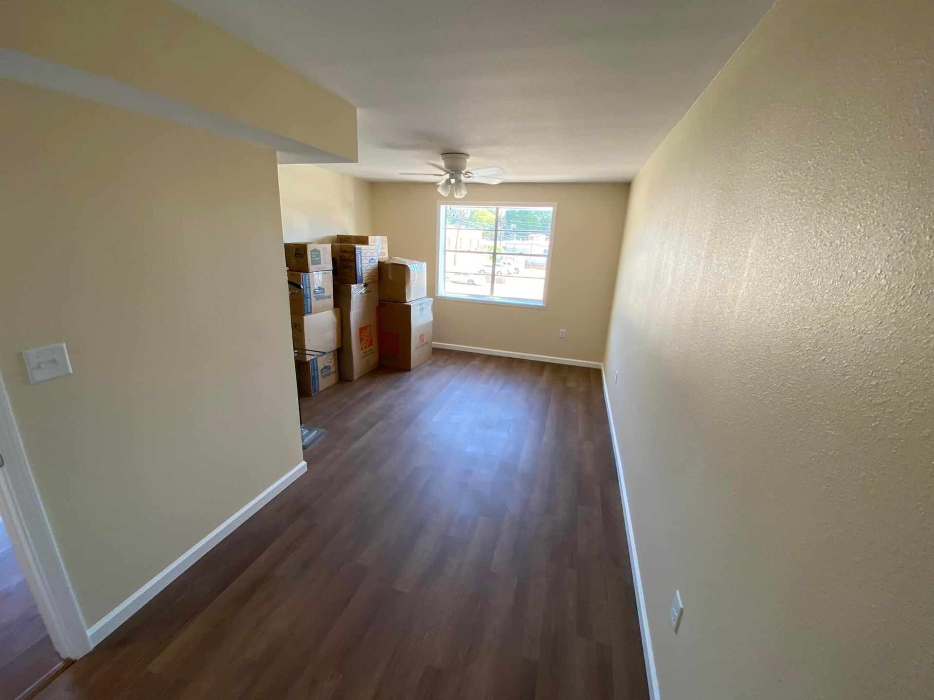 An empty room with boxes on the floor and a ceiling fan.