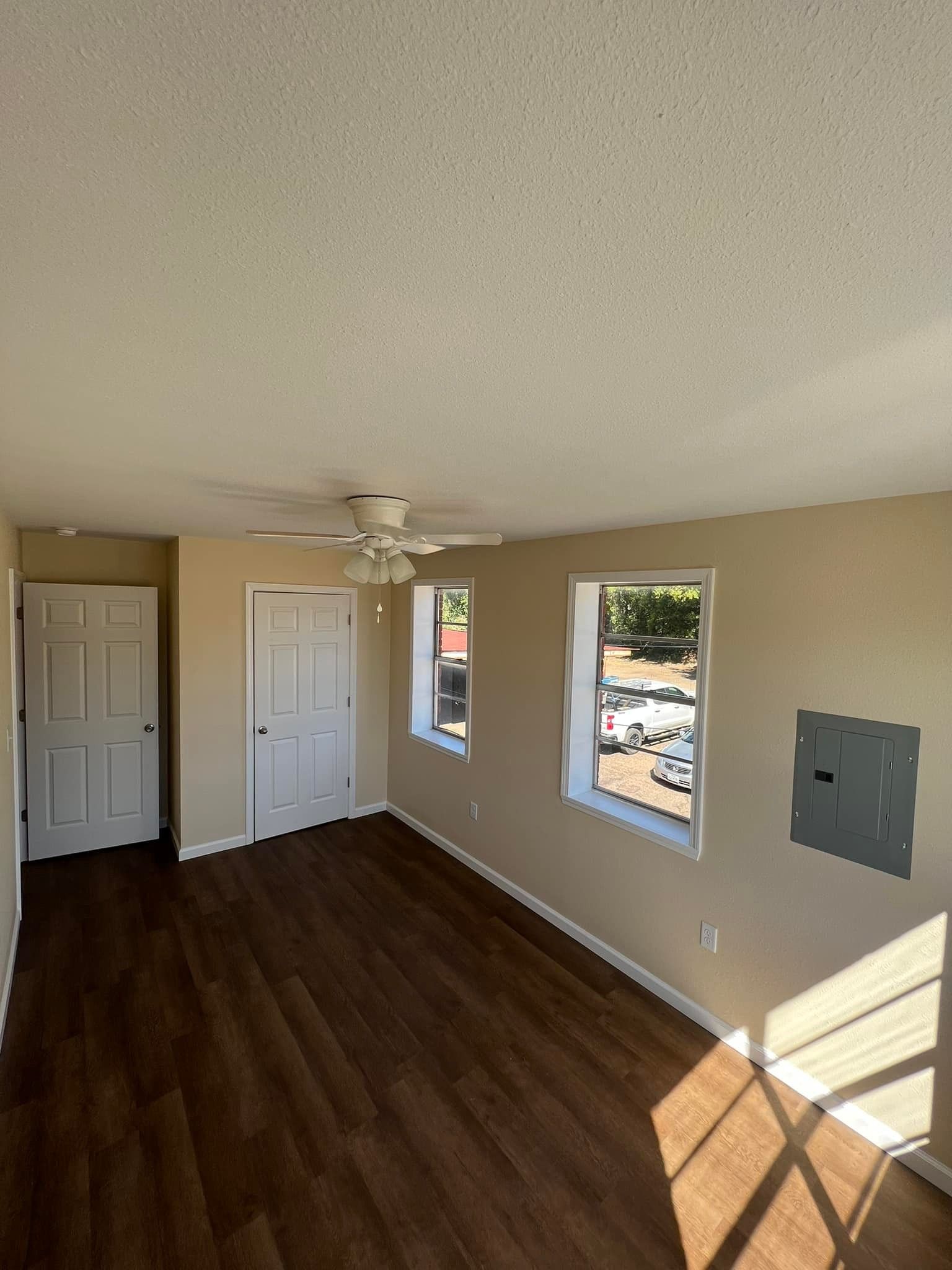 An empty living room with hardwood floors and a ceiling fan.