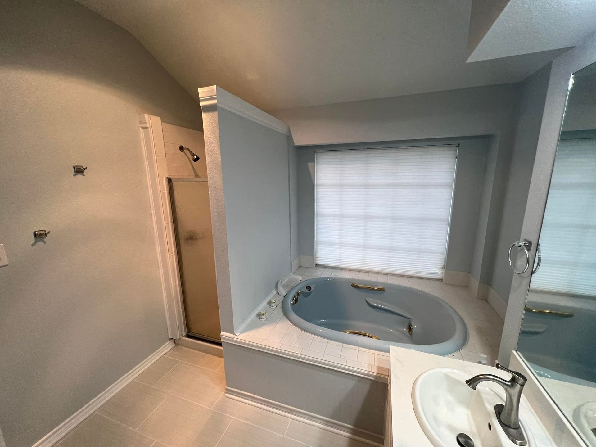 A bathroom with a tub , sink , mirror and shower.