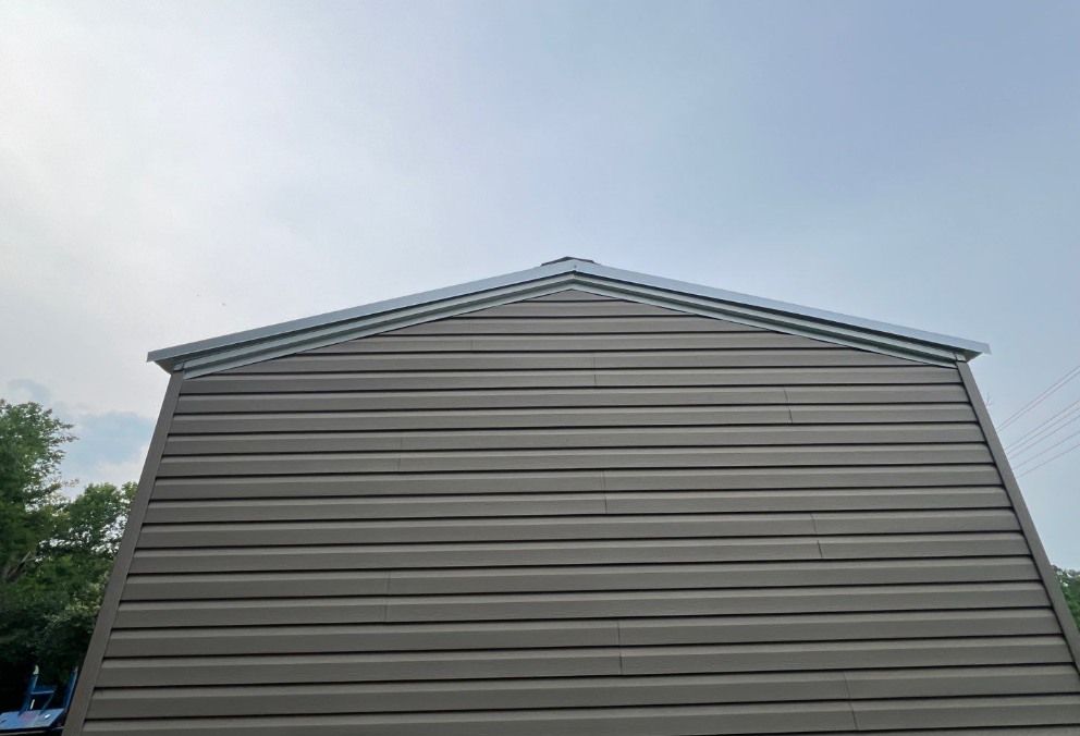A gray garage with a metal roof and a blue sky in the background.