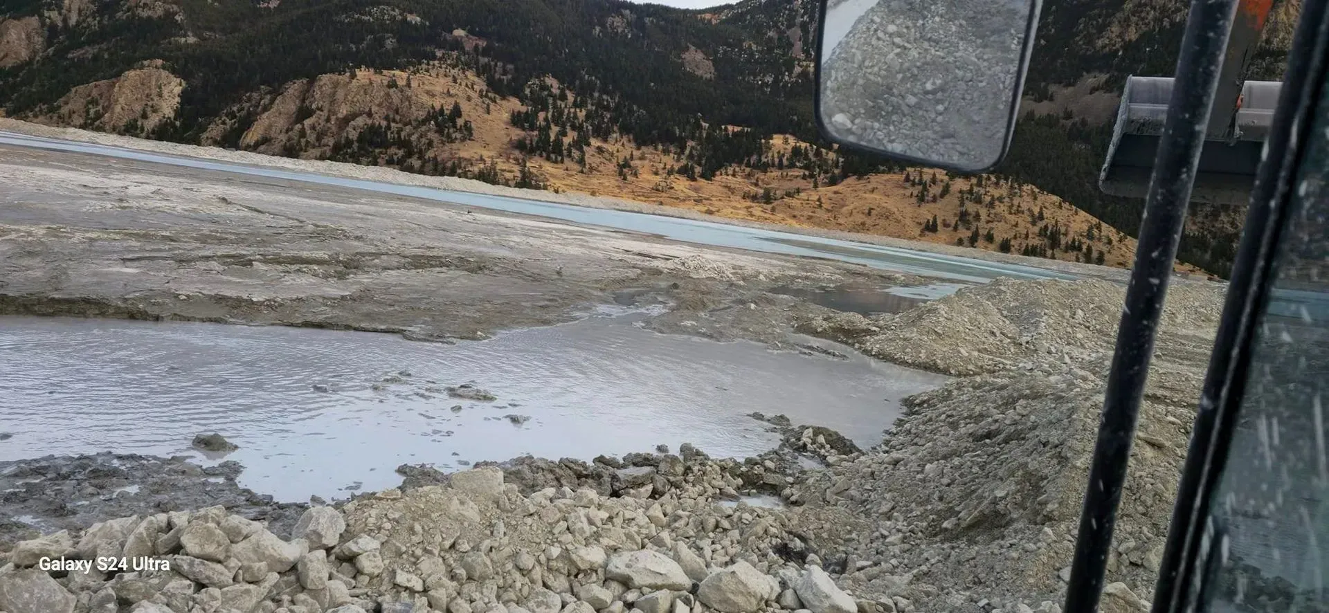 View from inside a vehicle, overlooking wet earth and brown soil.