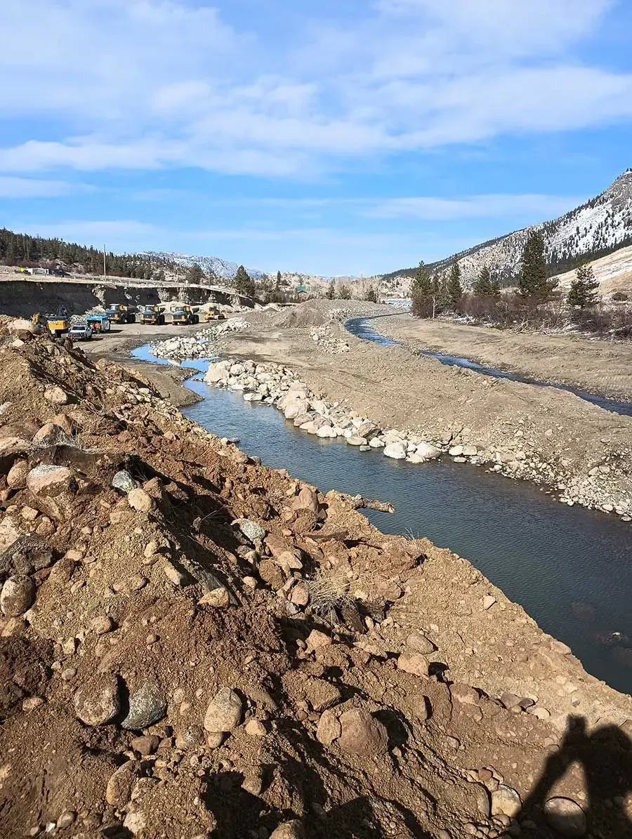 River flowing through a rocky landscape, with construction equipment visible.