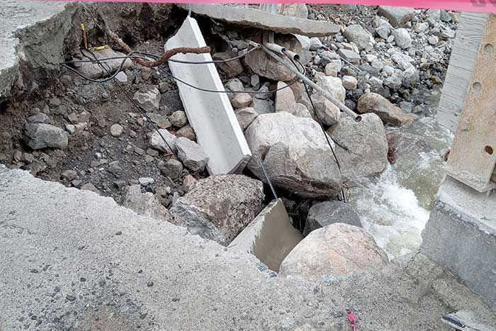 Collapsed bridge section with rocks and flowing water visible.