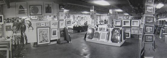 Black and white photo of an art gallery displaying various framed pictures and sculptures.