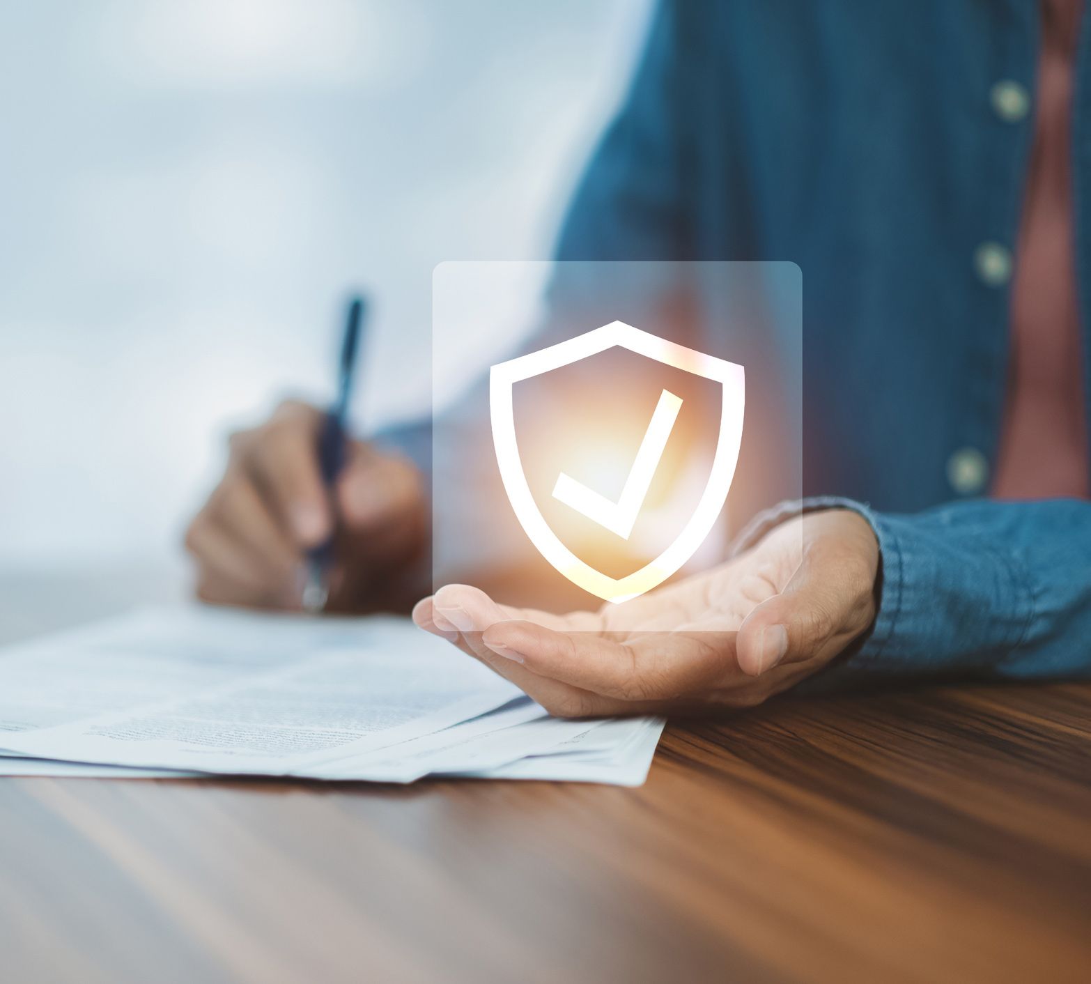 A person is holding a shield with a check mark on it while signing a document.