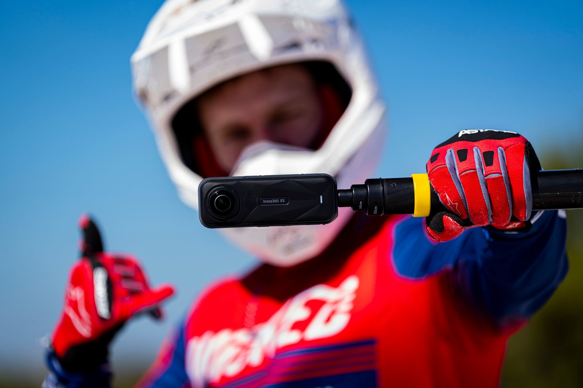 A person wearing a helmet and gloves is holding a camera.