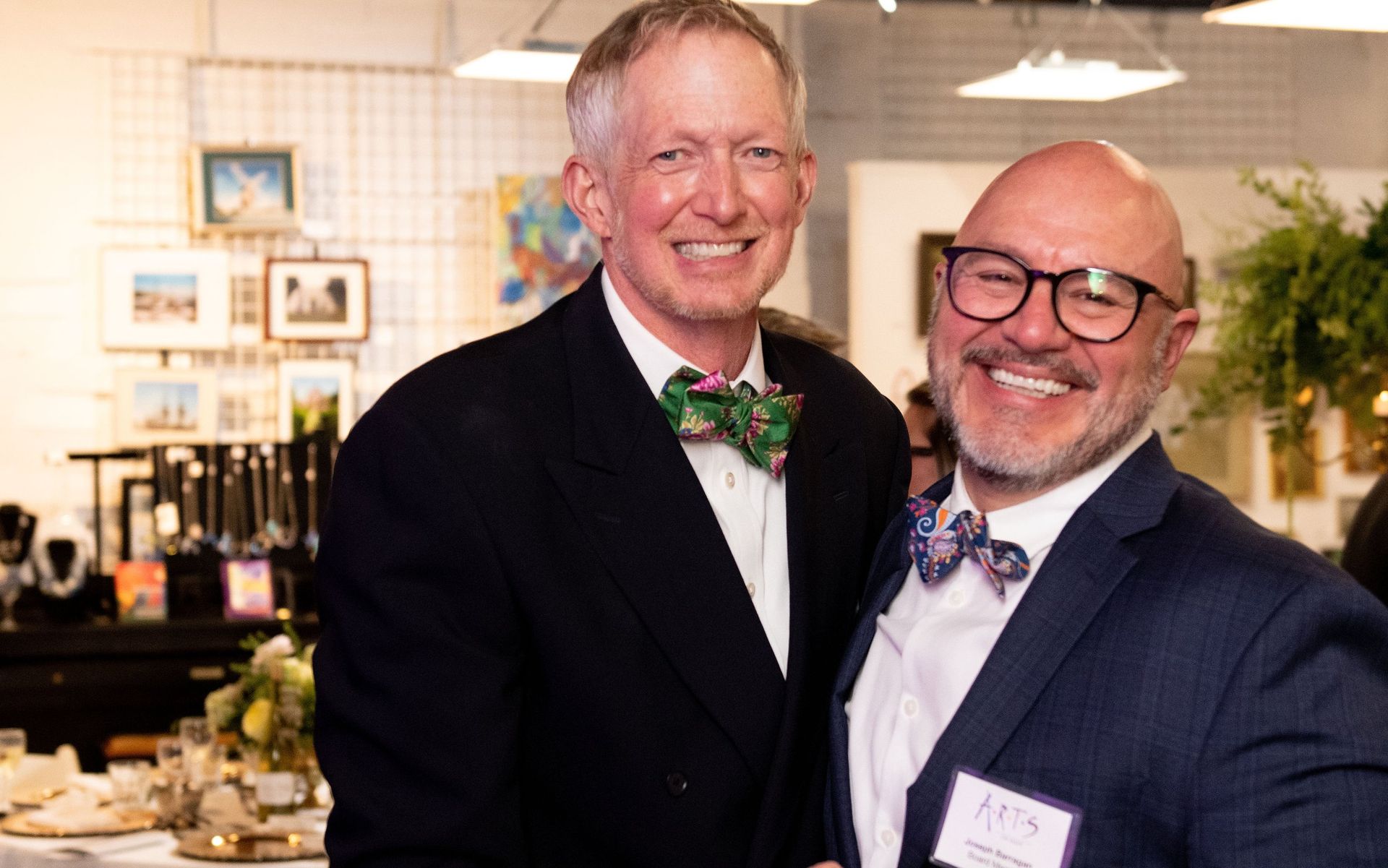Two men in suits and bow ties are posing for a picture.