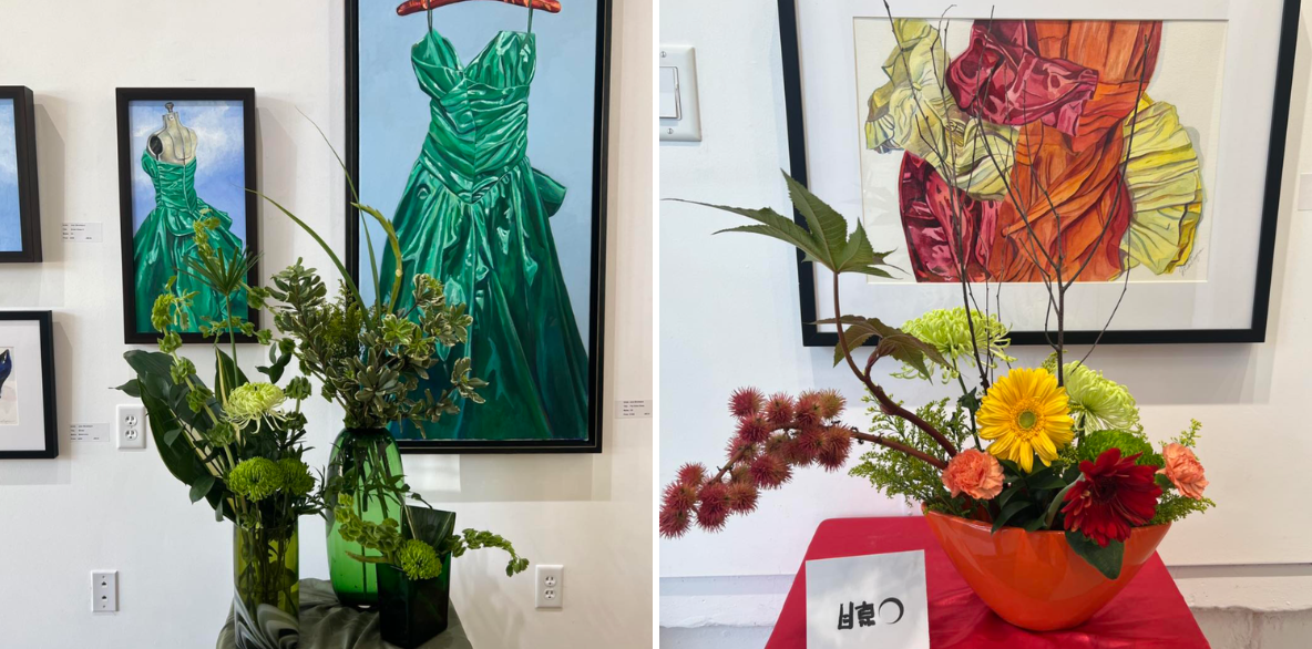 Floral arrangements displayed in an art gallery next to paintings featuring dresses.