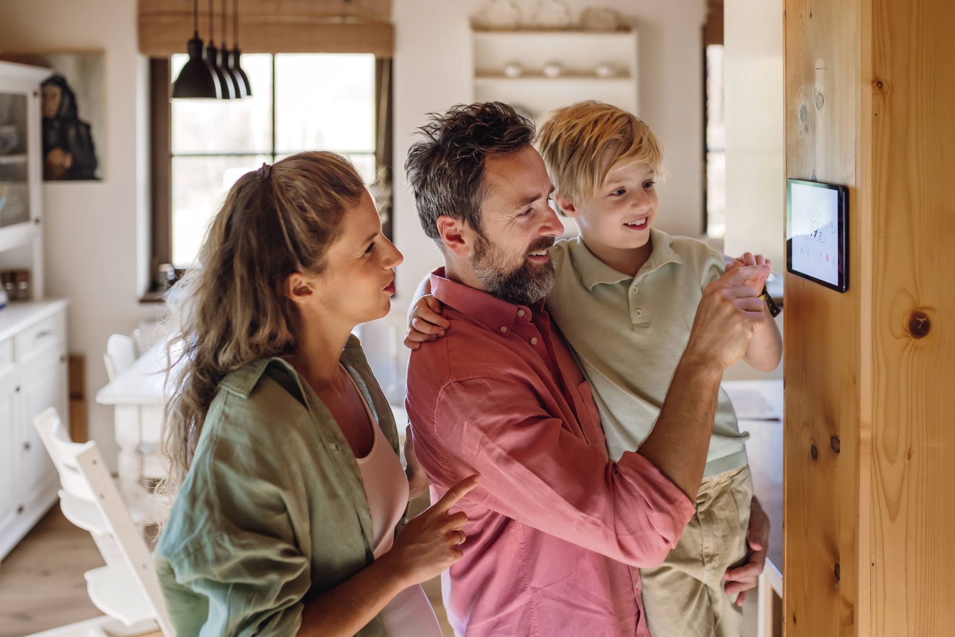 A family of three gathered around their new smart thermostat in their residence near Somerset, KY