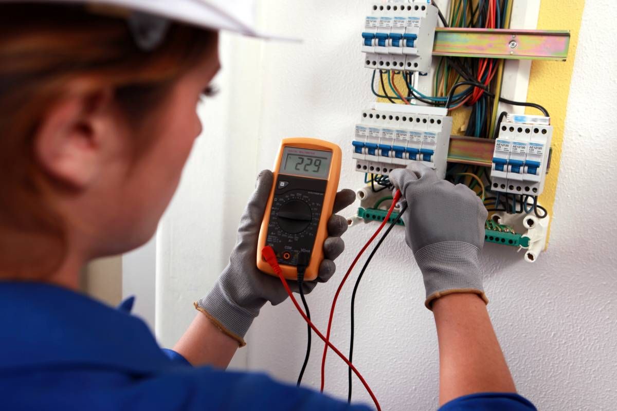 A professional electrician is inspecting a fuse box in a school to ensure safety and functionality near Somerset, KY