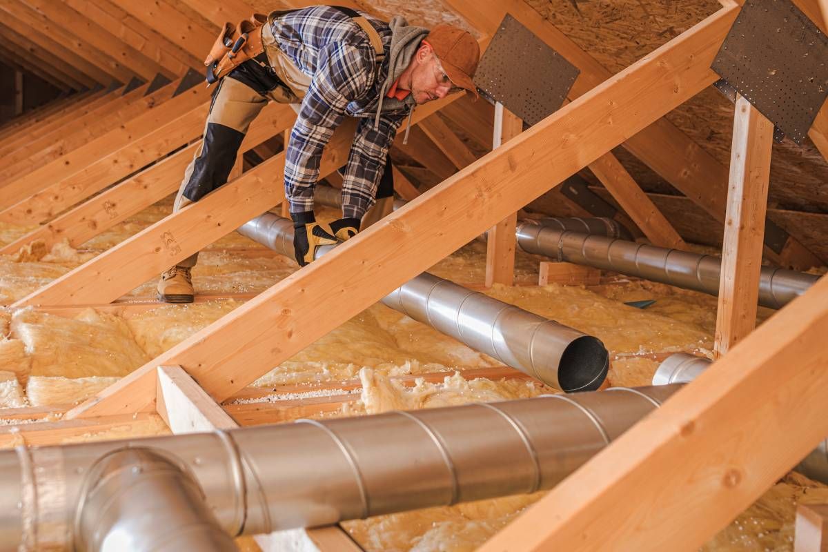 An expert HVAC technician working in a new residential construction build, installing ductwork in an attic near Somerset, KY