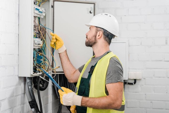 An expert technician wearing a white hardhat, working on commercial electric services and holding a clipboard near Somerset, KY