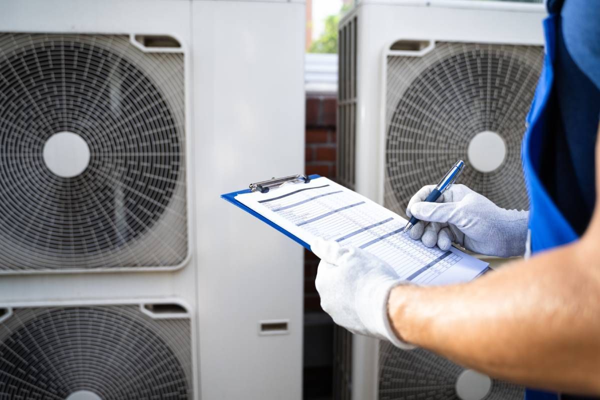 Expert HVAC technician performing routine maintenance on commercial HVAC systems with a blue clipboard and checklist near Somerset, KY