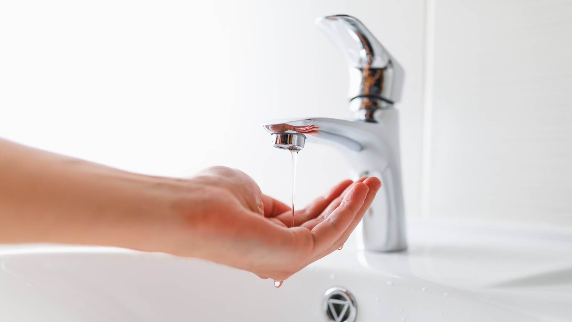 A white sink with a hand underneath a faucet with a low water pressure stream at Epperson Inc. in So