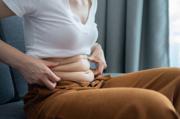 A woman is sitting on a couch holding her belly.