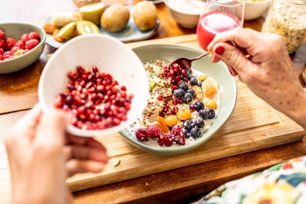 A person is eating a bowl of fruit and oatmeal with a spoon.