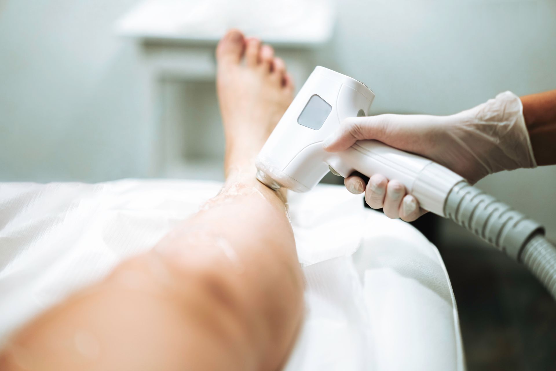 A woman is getting a laser hair removal treatment on her leg.