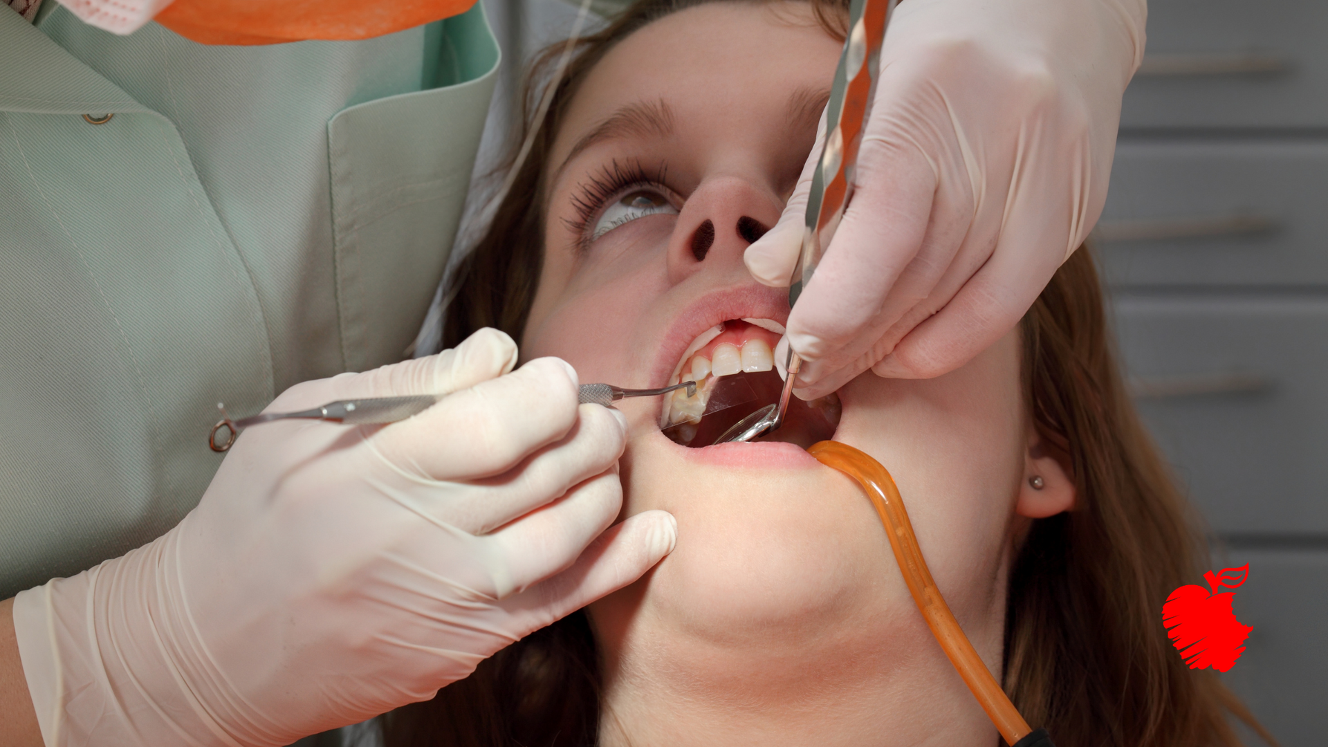 A young girl is getting her teeth examined by a dentist.