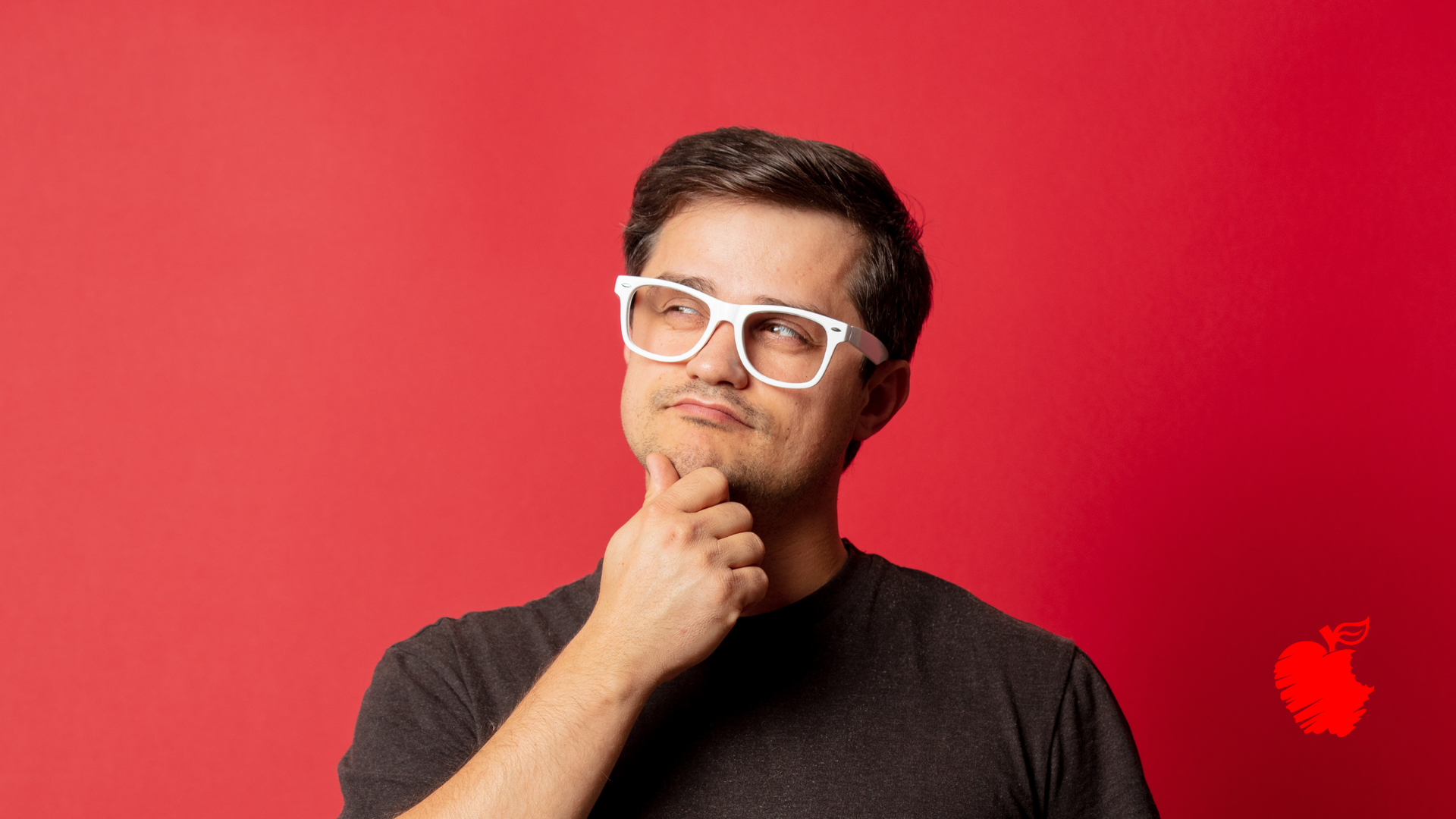 A man wearing glasses and a black shirt is thinking.