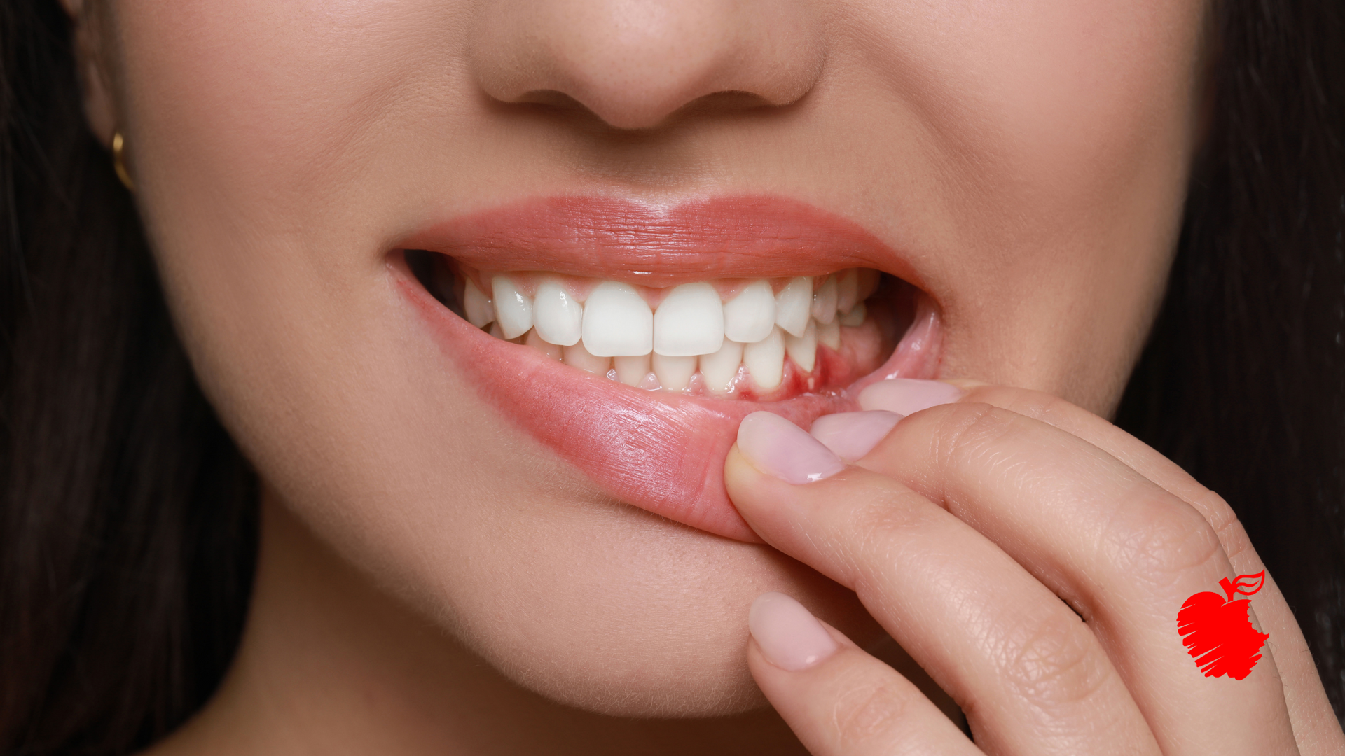 A close up of a woman 's mouth with her hand on her teeth.