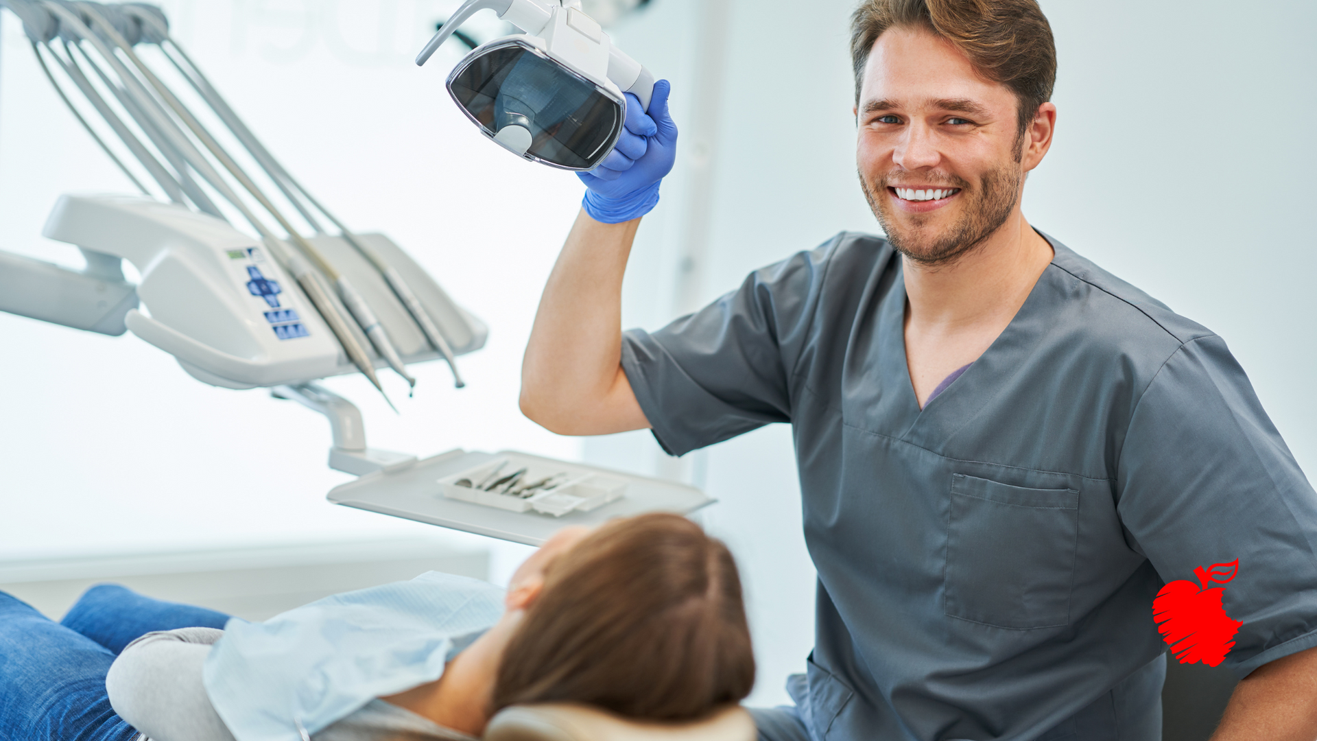 A dentist is holding an x-ray of a patient in a dental chair.