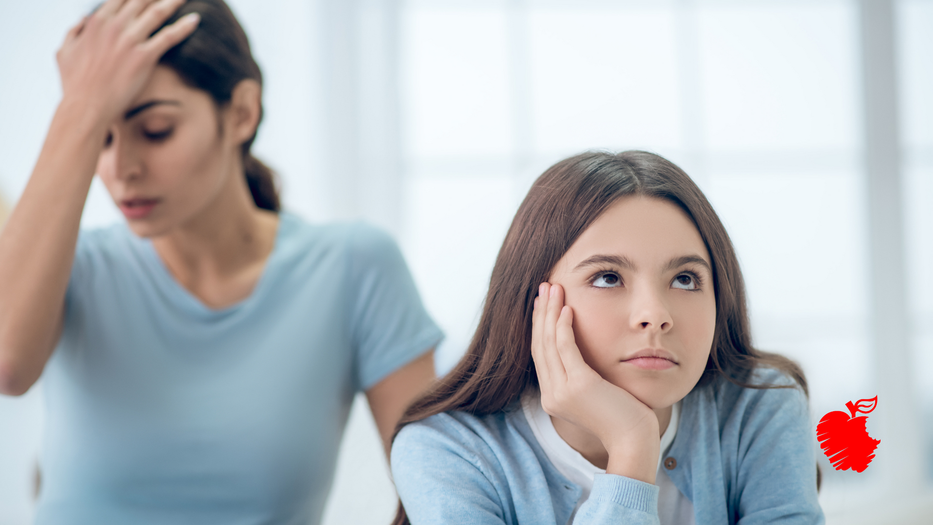 Two women are sitting next to each other and one of them is holding her head.