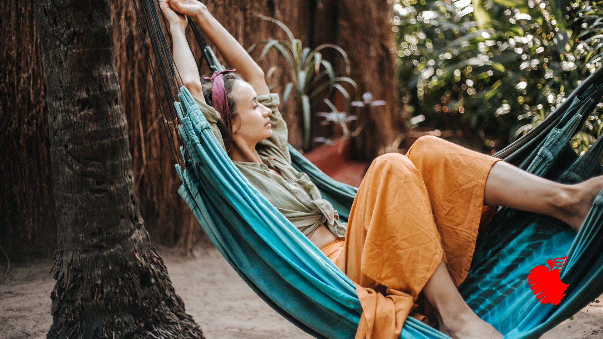 A woman is laying in a hammock with her arms outstretched.