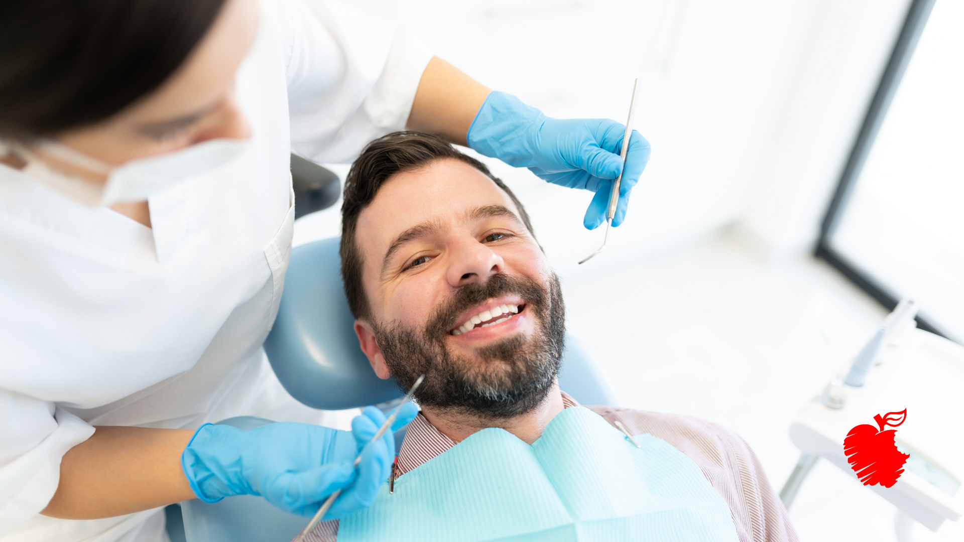 A man is sitting in a dental chair while a dentist examines his teeth.