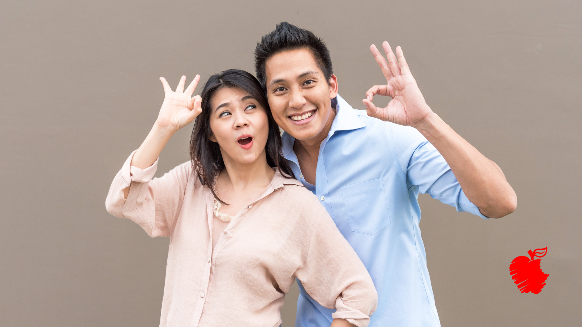 A man and a woman are standing next to each other and making an ok sign.