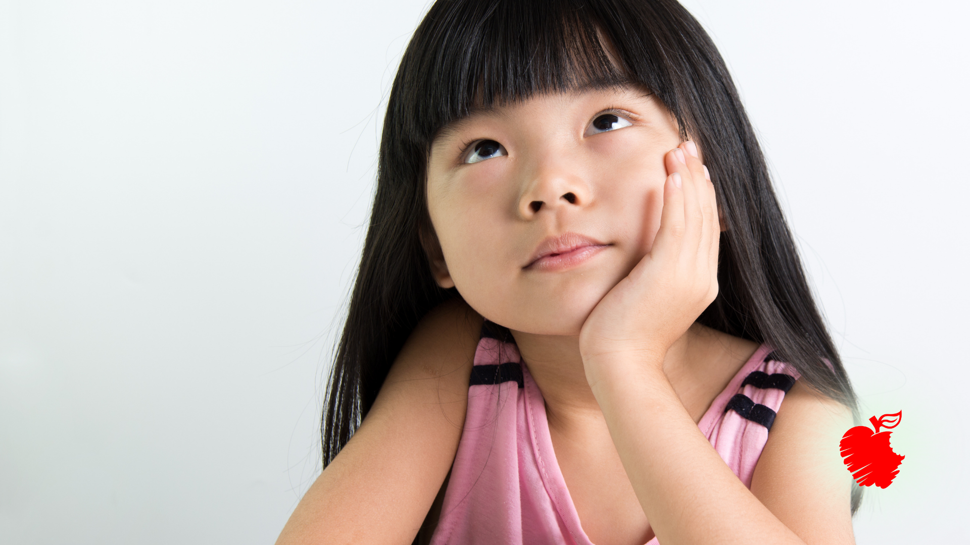 Girl with long black hair, wearing pink top, gazes upward with hand on cheek, against a white background.