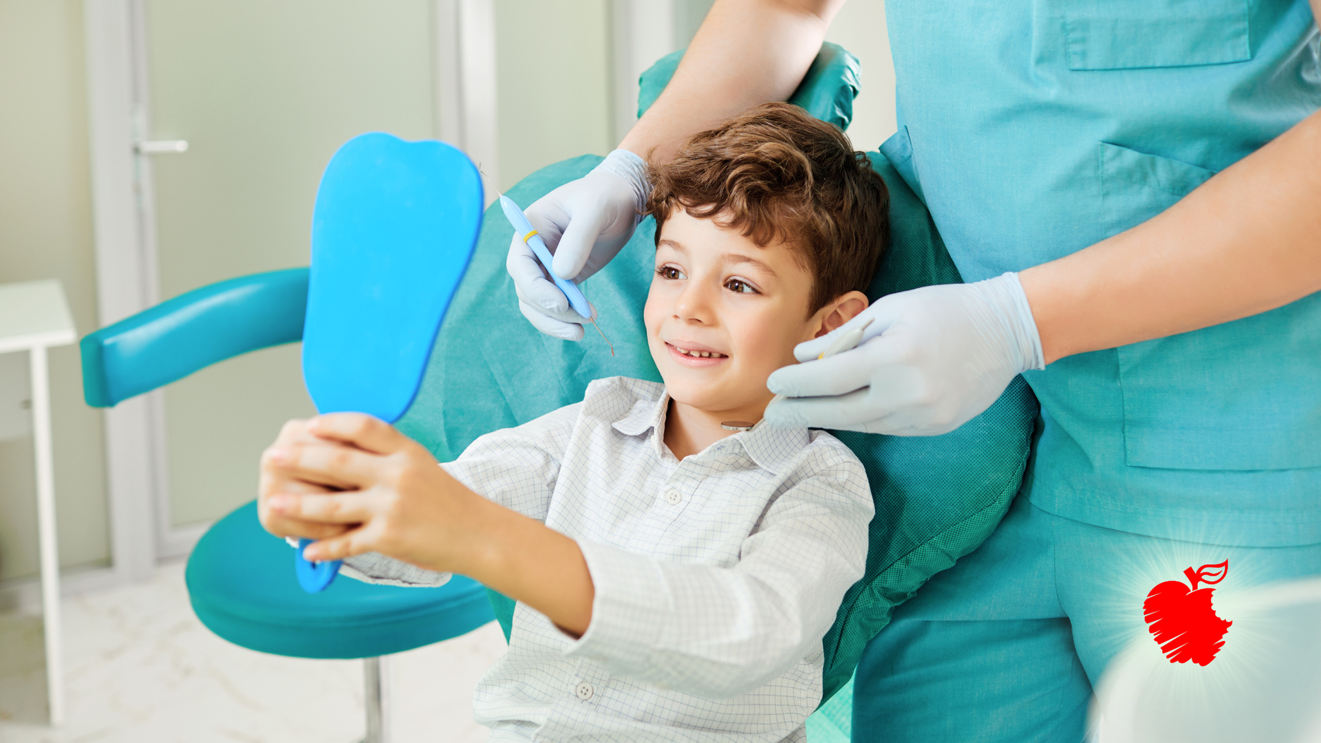 Boy in dental chair looking in a mirror held by dentist. Dental office setting, turquoise chair and equipment.