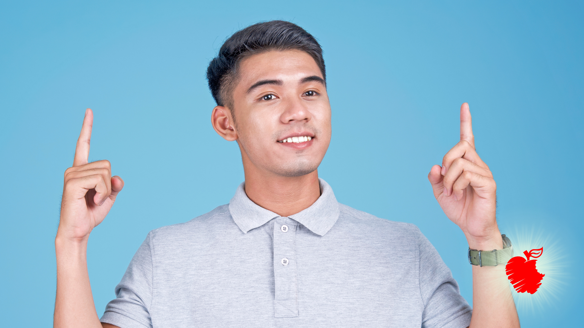 Young man in gray shirt points upwards with both hands; blue background, apple-shaped graphic on wrist.