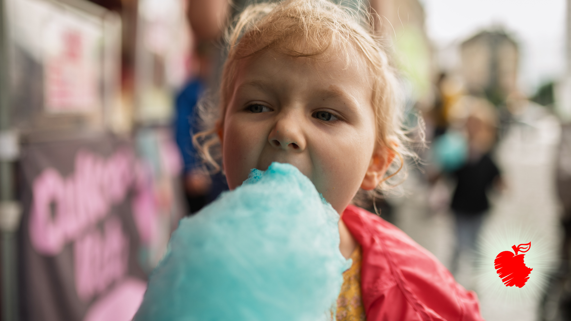 Girl eating blue cotton candy at an outdoor event.