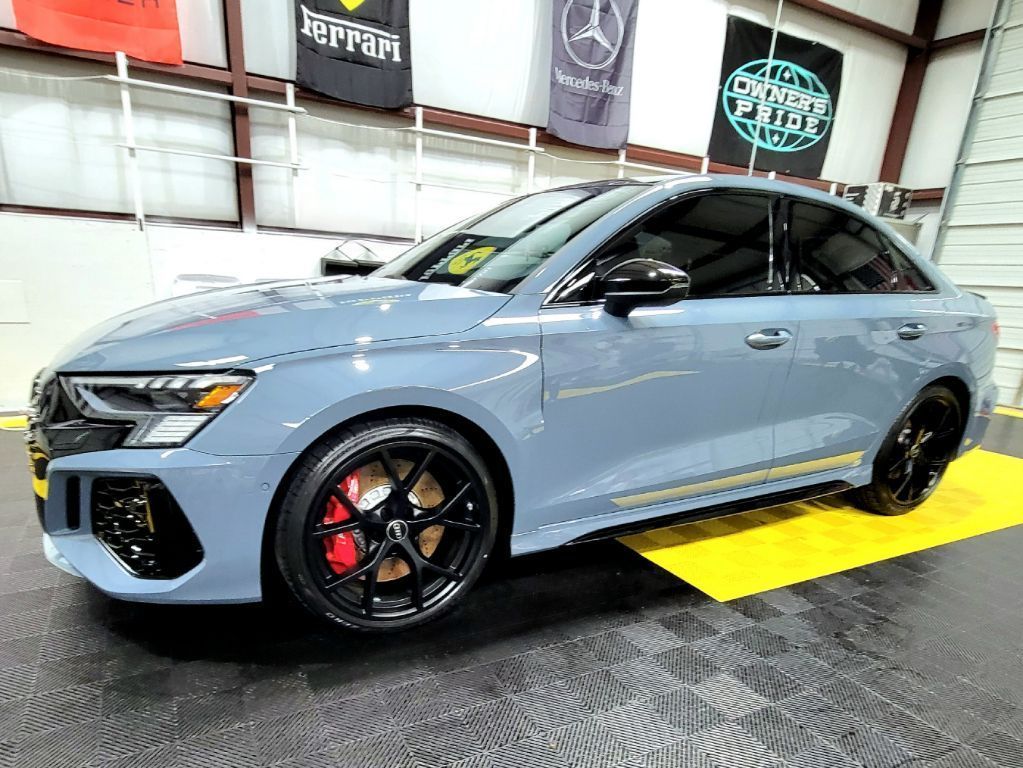 Gray Audi sedan with black wheels and red brake calipers parked indoors.