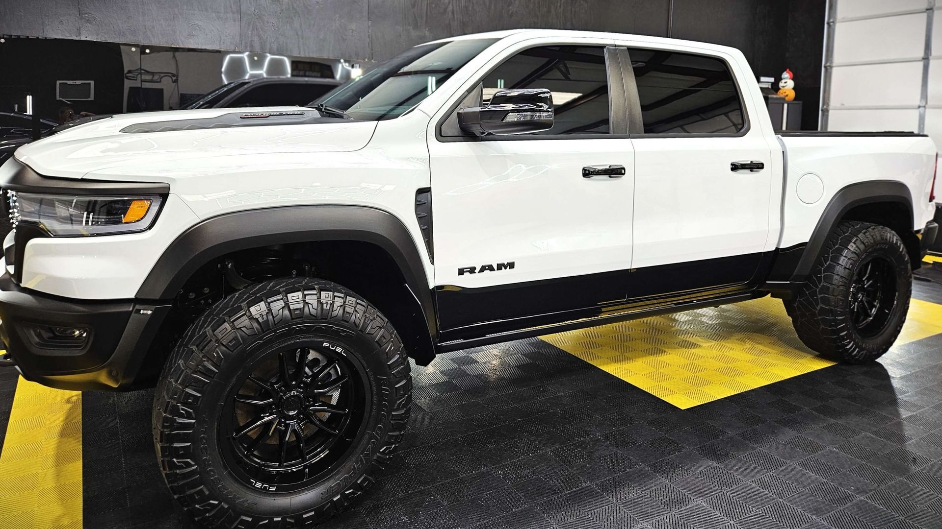 A white ram truck with black wheels is parked in a garage.