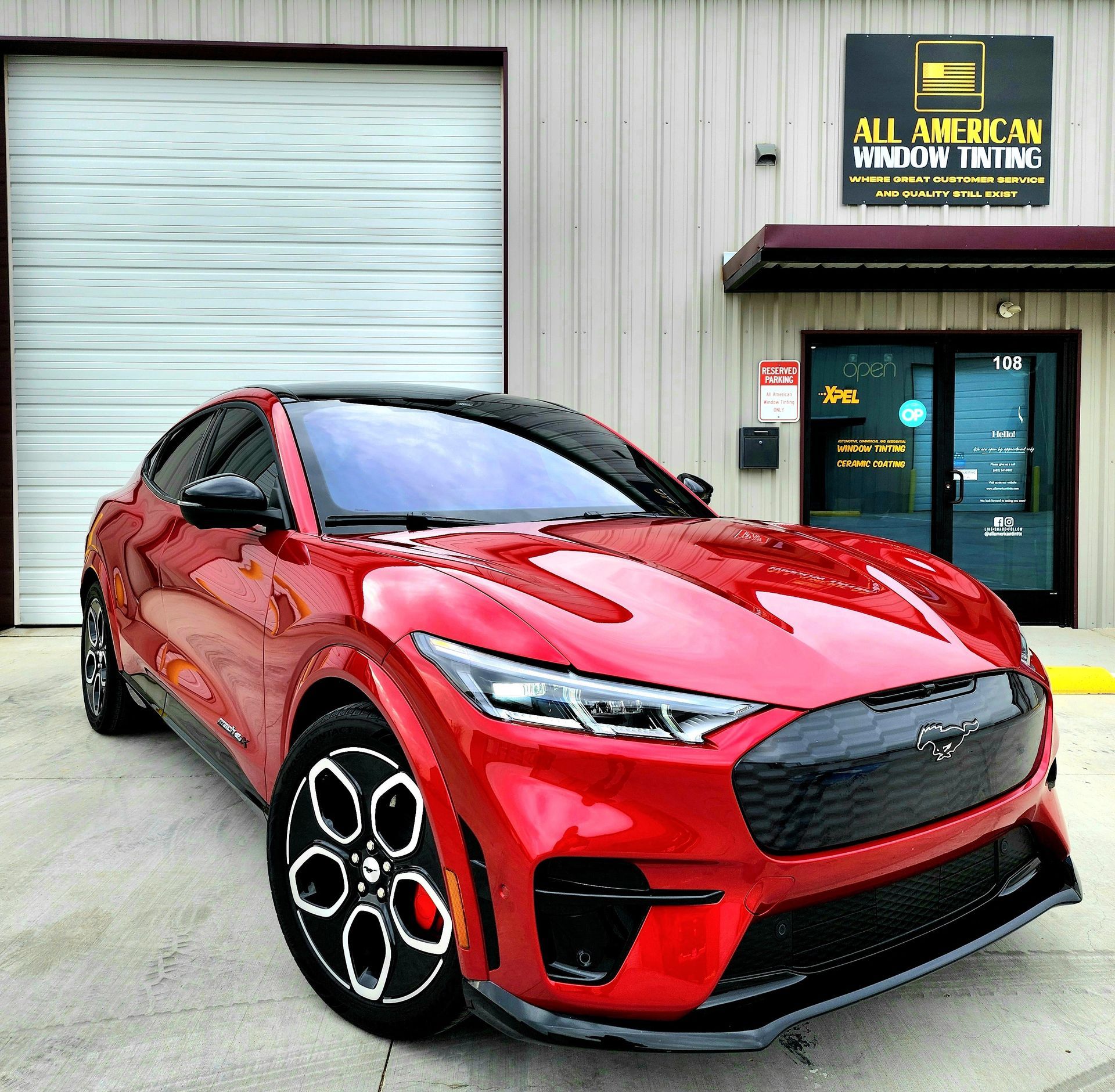Red Ford Mustang Mach-E parked in front of an 