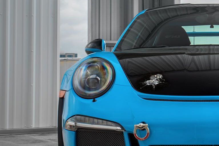 Blue and black sports car with round headlight and towing ring.