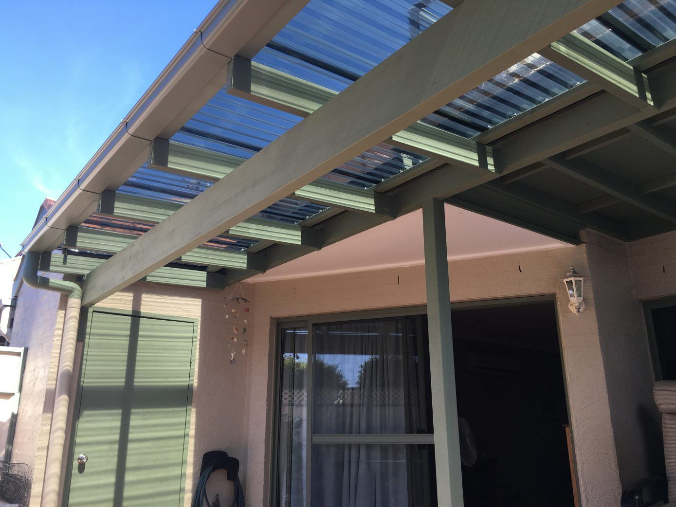 A Covered Porch With A Clear Roof And A Sliding Glass Door — Newcastle Patio Covers In Wallsend, NSW