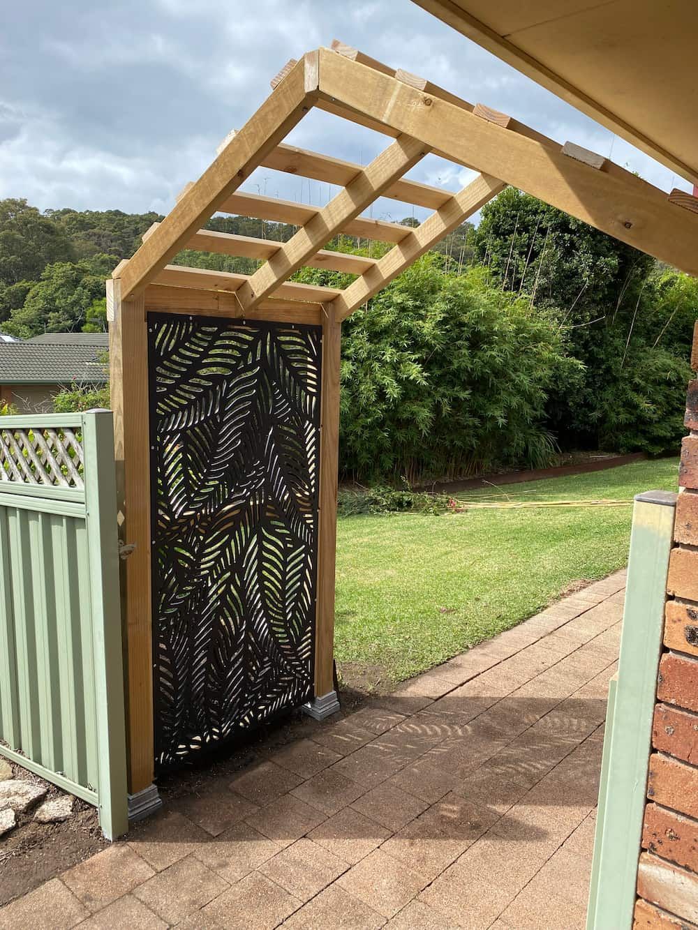 A Brick Building With A Metal Structure In Front Of It — Newcastle Patio Covers In Wallsend, NSW