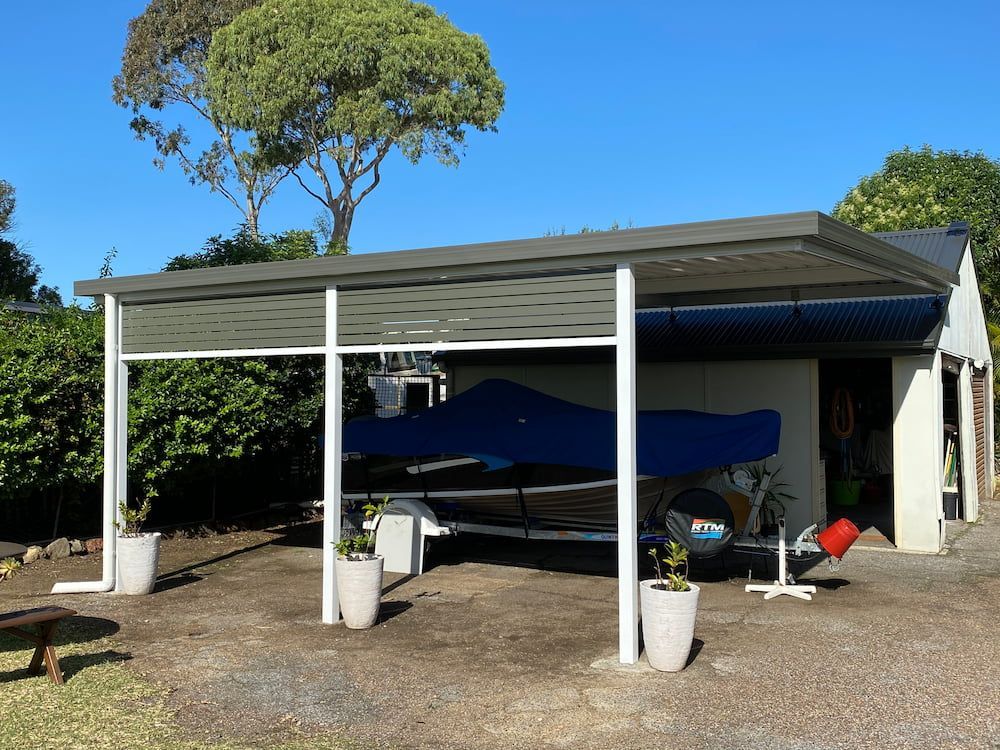 A Boat Is Parked Under A Canopy In Front Of A House — Newcastle Patio Covers In Lake Macquarie, NSW