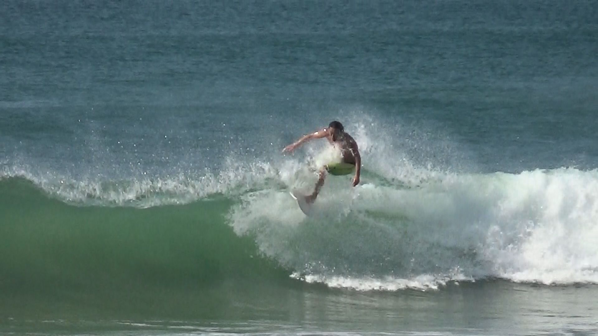 Surfer riding a wave; white water and turquoise water; sunny day.
